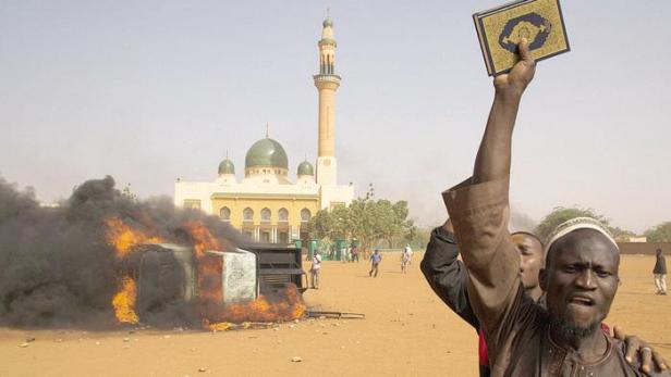 Un uomo alza un Corano durante una protesta in Niger contro il presidente Issoufou per la sua partecipazione al corteo anti-terrorismo di Parigi
